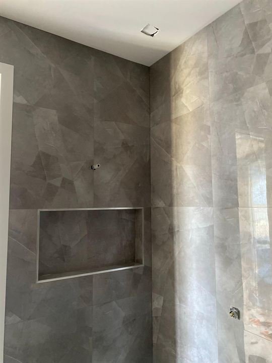 Marble-look tiled shower with a built-in niche