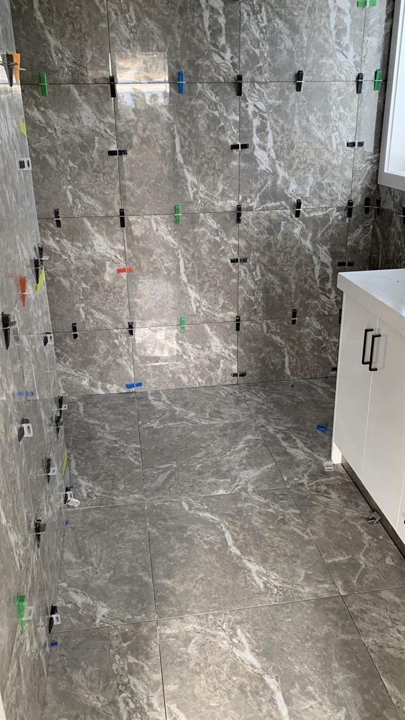 Marble-look bathroom walls and floor being tiled with levelling clips