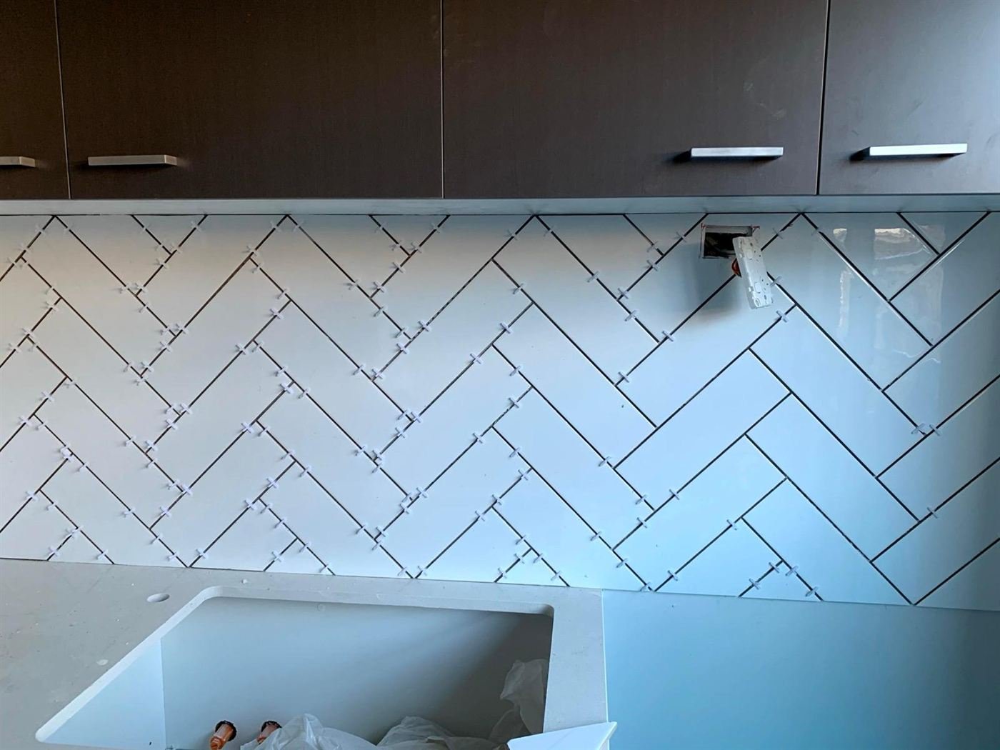 White herringbone tile splashback with dark grout