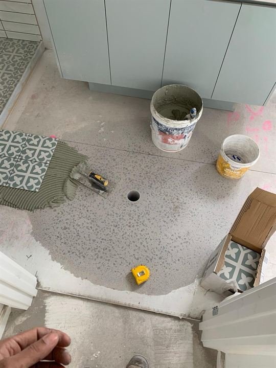 Sand and cement screed bed with pattern tiles being laid